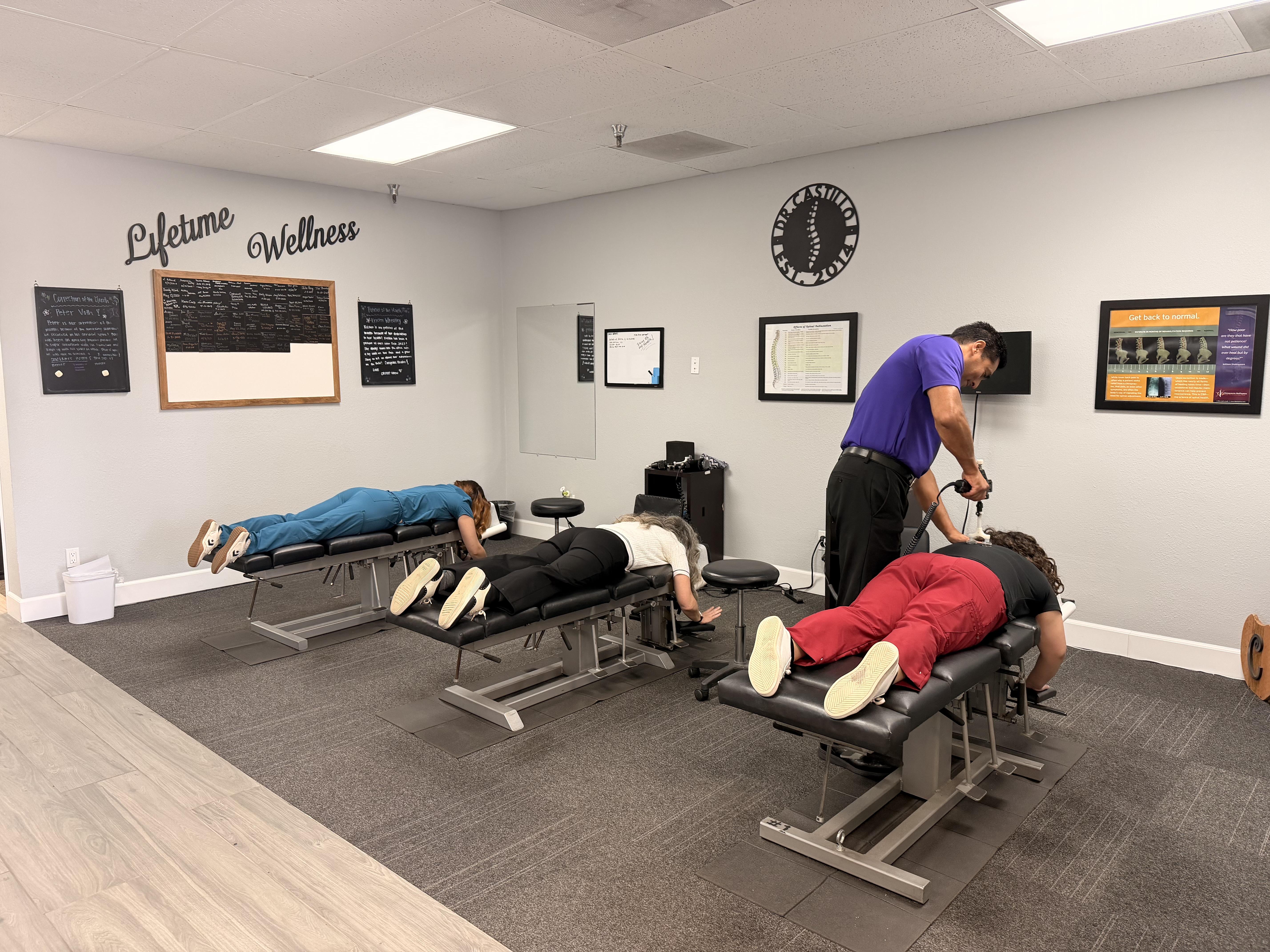 Dr. Castillo providing instrument-assisted chiropractic care to patients in the office